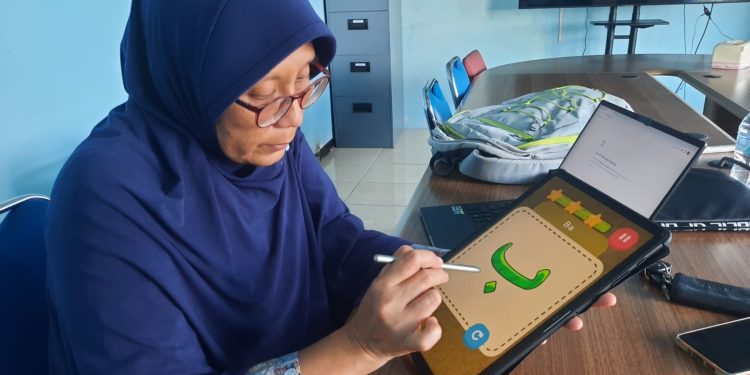 Dr Eng Nanik Suciati SKom MKom saat mempraktikkan menggunakan aplikasi Pembelajaran Huruf Hijaiyah yang dikembangkan (Foto: Humas ITS)
